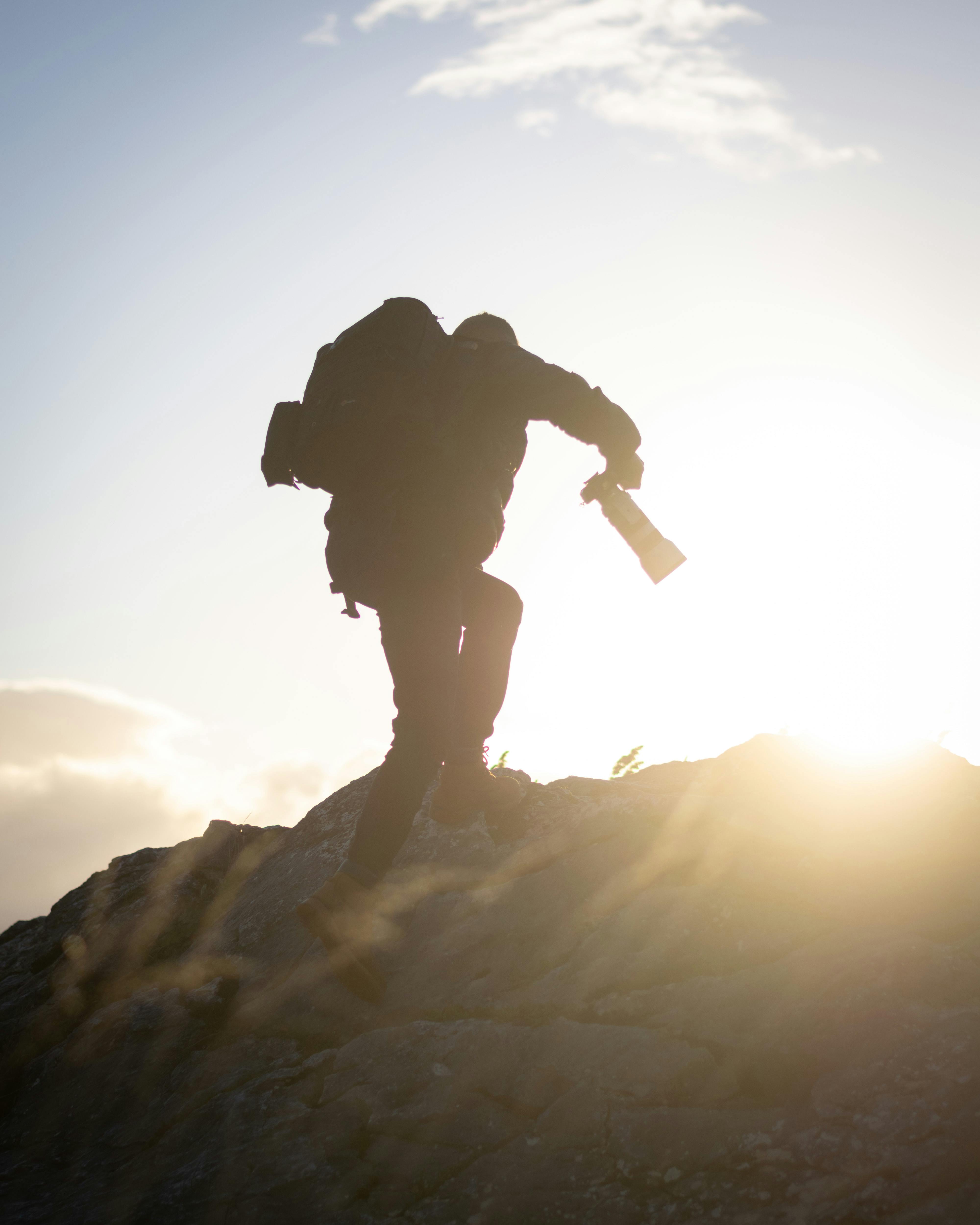 Photographer composing a landscape shot with a single lens on a mountain trail