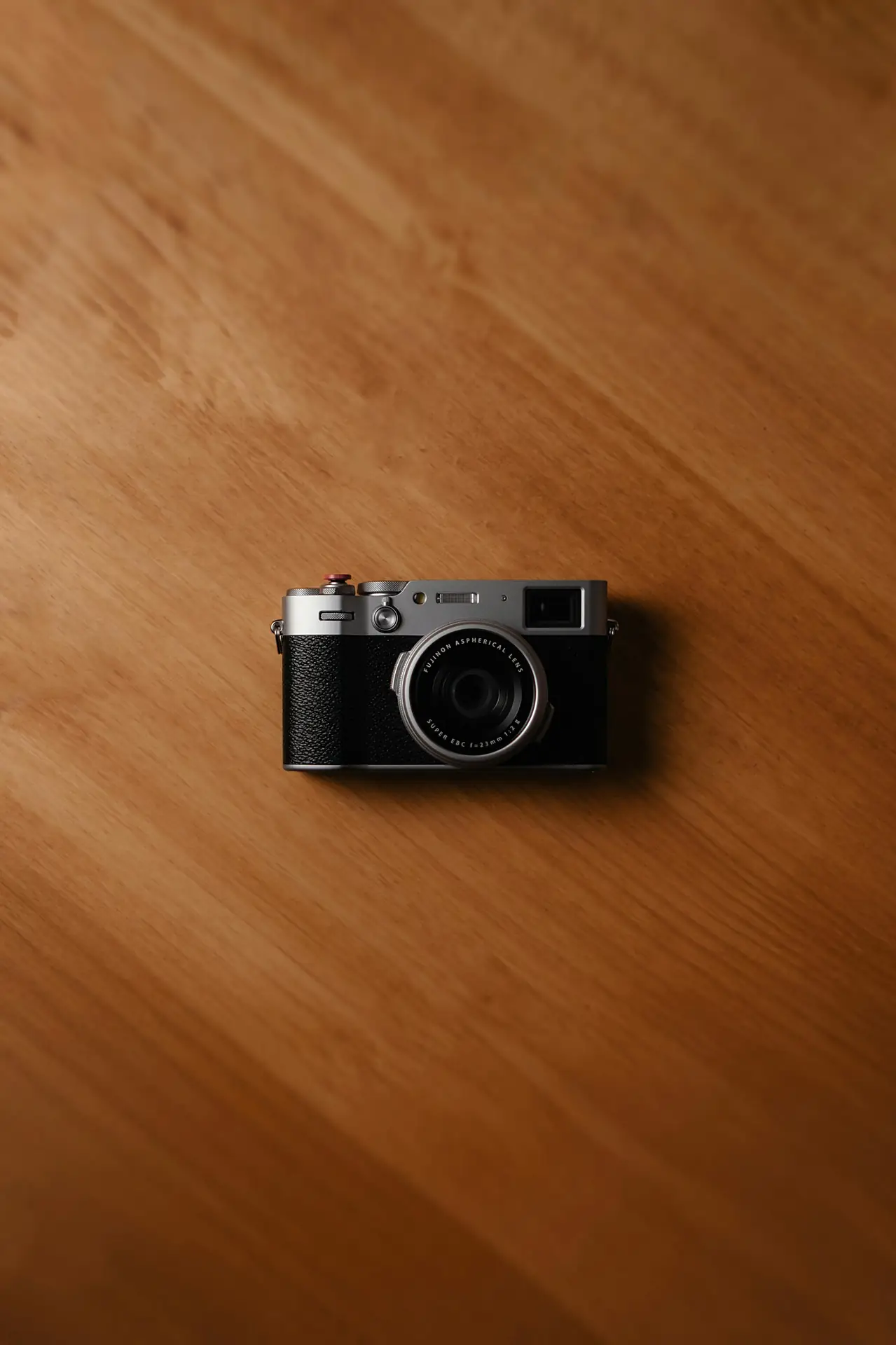 Fujifilm-stijl camera met voelbare draaiknoppen op een houten tafel